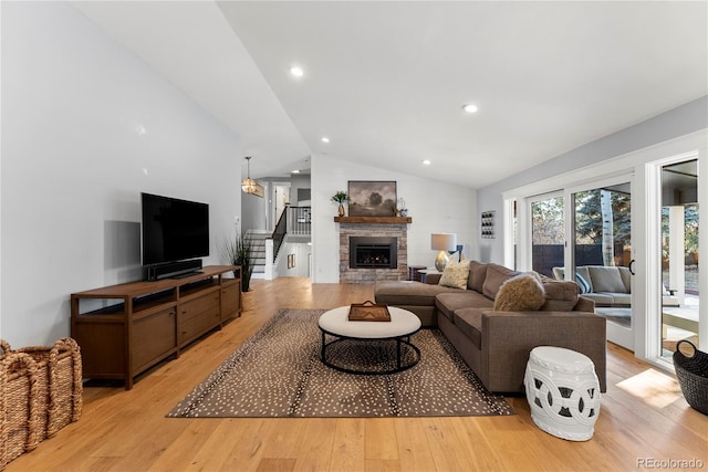 living room with recessed lighting, stairway, light wood-style floors, a fireplace, and vaulted ceiling