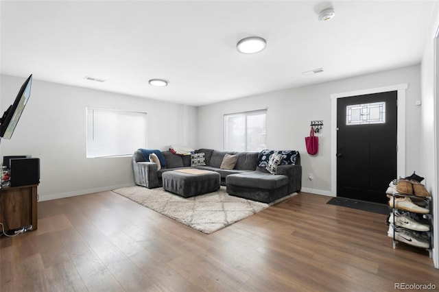 living room with visible vents, baseboards, and wood finished floors