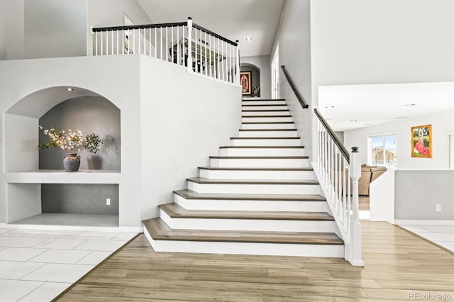 stairs with hardwood / wood-style floors and a high ceiling