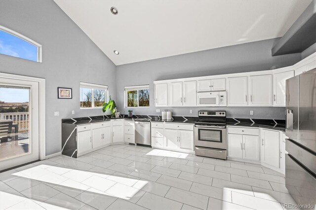 kitchen featuring white cabinetry, high vaulted ceiling, light tile patterned floors, and appliances with stainless steel finishes