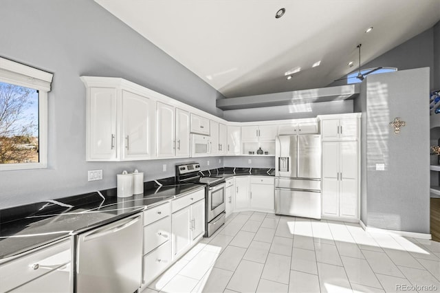 kitchen with appliances with stainless steel finishes, light tile patterned floors, white cabinetry, and vaulted ceiling