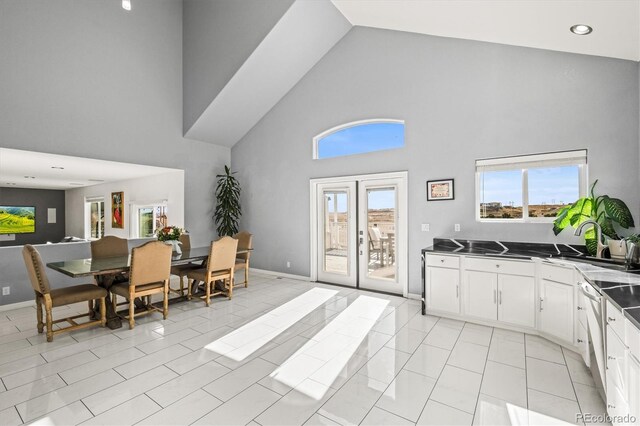 kitchen featuring dishwasher, high vaulted ceiling, white cabinets, sink, and light tile patterned floors