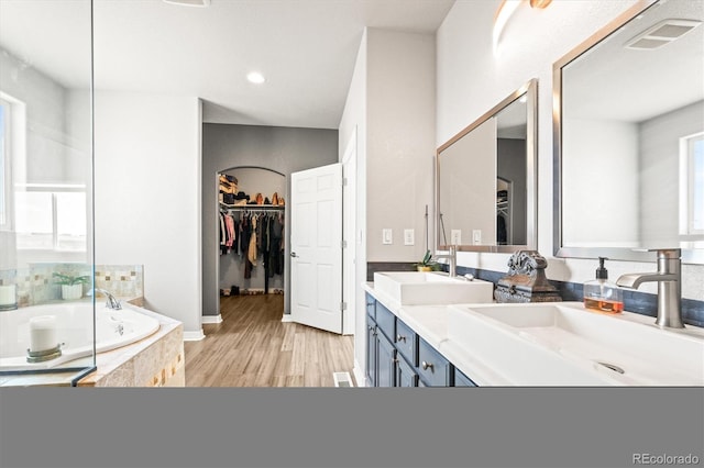 bathroom with tiled tub, vanity, and hardwood / wood-style flooring