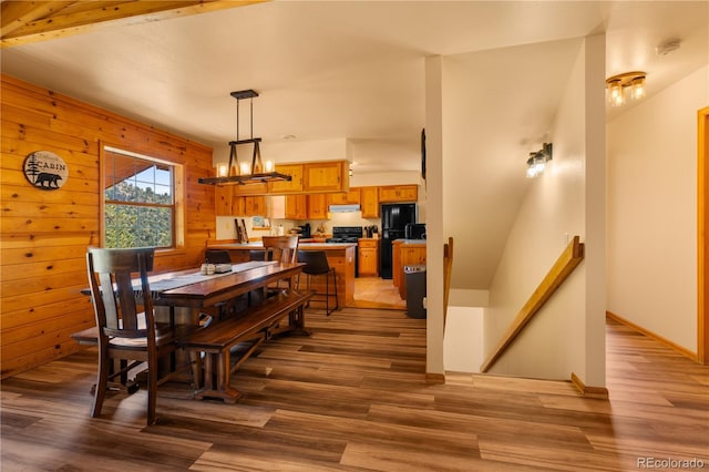 dining space with beamed ceiling, wood walls, a chandelier, and hardwood / wood-style flooring