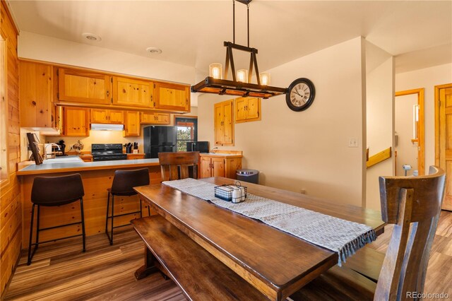 dining area featuring an inviting chandelier, lofted ceiling, wood walls, and hardwood / wood-style flooring