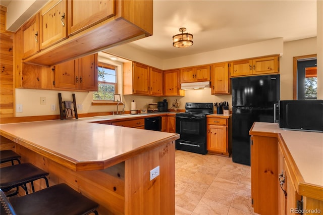 kitchen featuring sink, a kitchen bar, kitchen peninsula, and black appliances