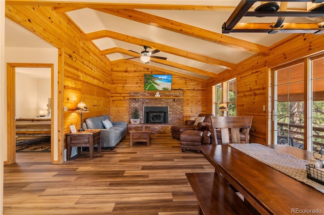 living room with a brick fireplace, hardwood / wood-style flooring, lofted ceiling with beams, and ceiling fan