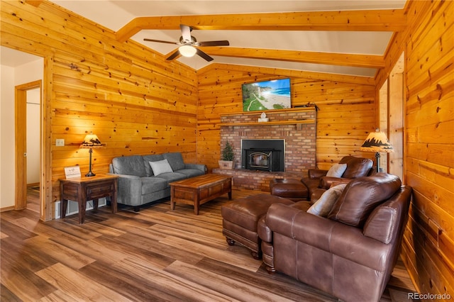 living room with lofted ceiling with beams, a fireplace, ceiling fan, hardwood / wood-style flooring, and wooden walls