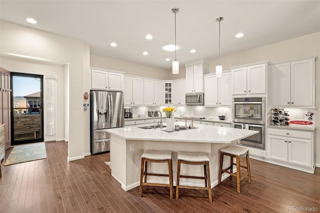 3418 New Haven Cir, Castle Rock, CO 80109 - kitchen featuring appliances with stainless steel finishes, a center island with sink, a sink, white cabinetry, and dark wood finished floors
