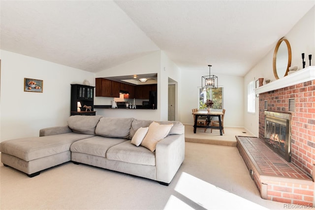 living room featuring vaulted ceiling, a notable chandelier, light colored carpet, and a fireplace