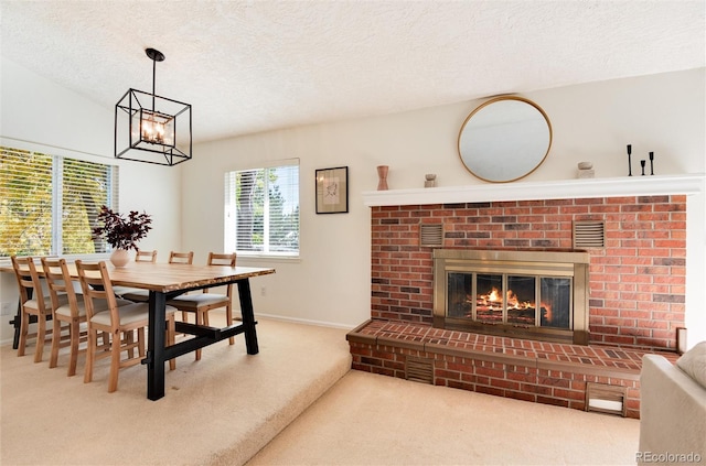 dining space with carpet, a textured ceiling, a fireplace, and an inviting chandelier