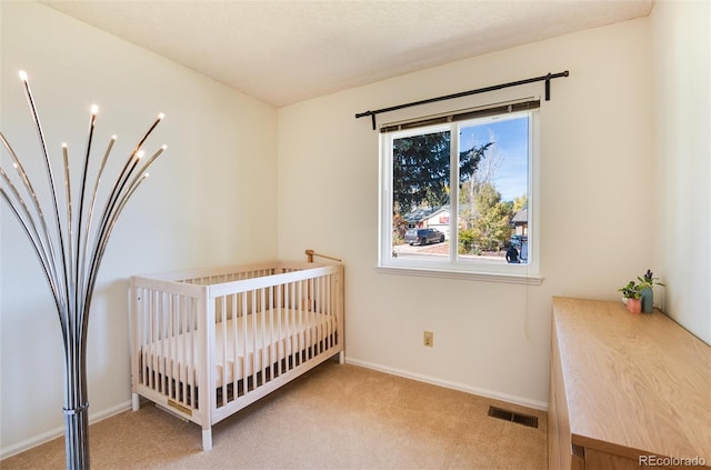 carpeted bedroom featuring a nursery area