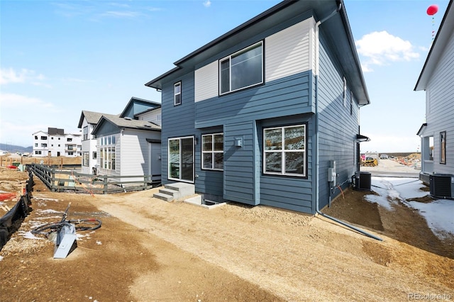 back of house featuring entry steps, central air condition unit, and fence