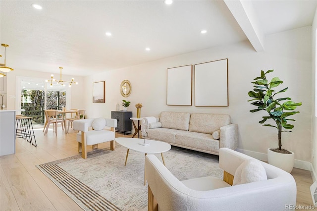 living room with beam ceiling, a notable chandelier, and light wood-type flooring