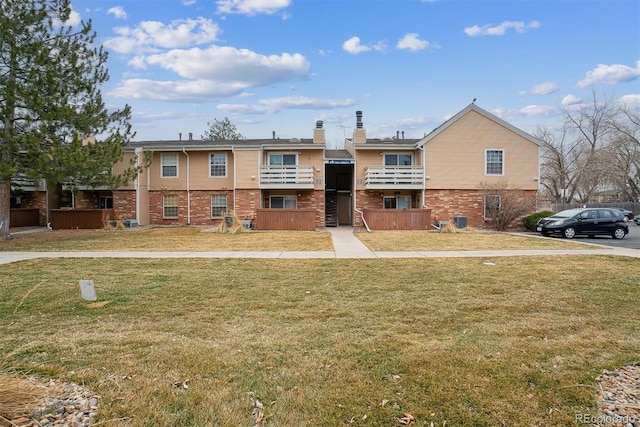 view of front of home with brick siding, a chimney, and a front yard