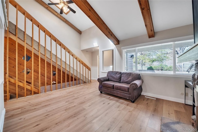 living area with a ceiling fan, baseboards, wood finished floors, beamed ceiling, and stairway