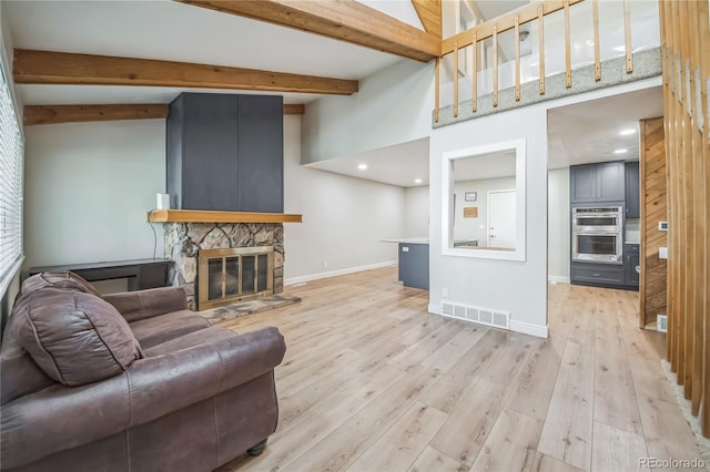 living room with visible vents, a fireplace, wood finished floors, baseboards, and beamed ceiling