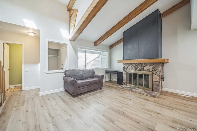 living area featuring vaulted ceiling with beams, baseboards, a fireplace, and light wood-type flooring