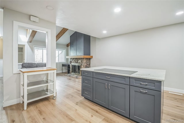 kitchen featuring a fireplace, gray cabinetry, baseboards, recessed lighting, and light wood-style flooring