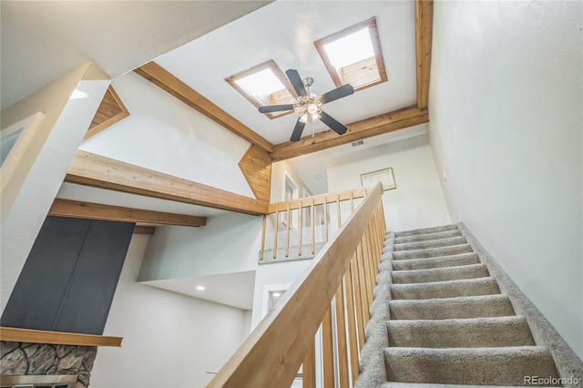 stairs with a ceiling fan, beamed ceiling, and high vaulted ceiling