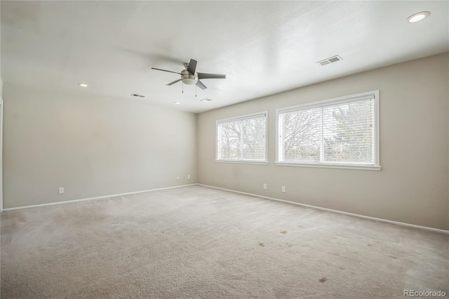 spare room featuring baseboards, ceiling fan, light colored carpet, and visible vents