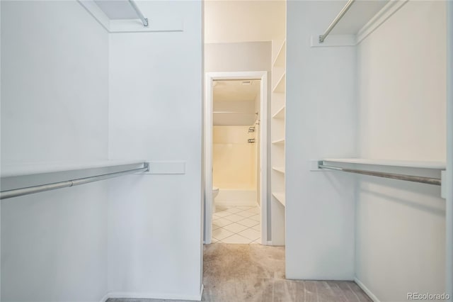 walk in closet with light carpet and light tile patterned floors