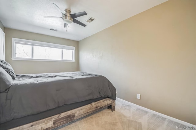 bedroom with ceiling fan, visible vents, light carpet, and baseboards