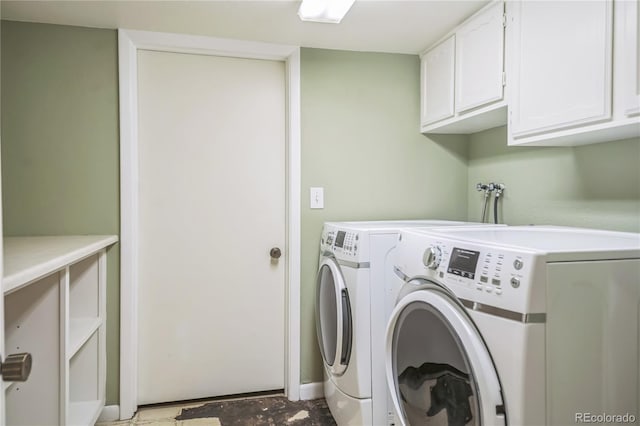 clothes washing area featuring washer and dryer, baseboards, and cabinet space