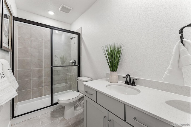 bathroom featuring a shower with door, tile patterned floors, vanity, and toilet