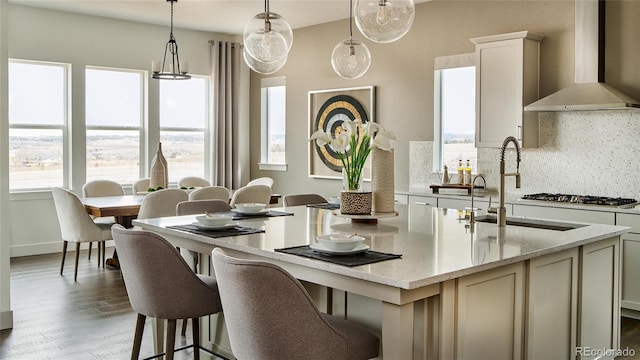 kitchen with wall chimney range hood, decorative light fixtures, a wealth of natural light, and dark hardwood / wood-style flooring