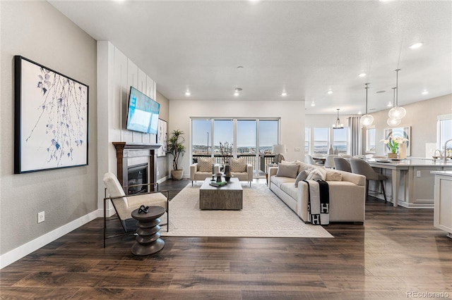 living room featuring a chandelier, dark wood-type flooring, and a large fireplace