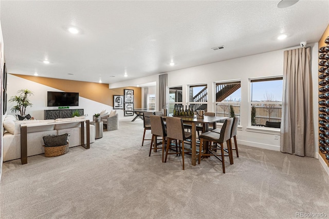 dining room with light carpet and a textured ceiling