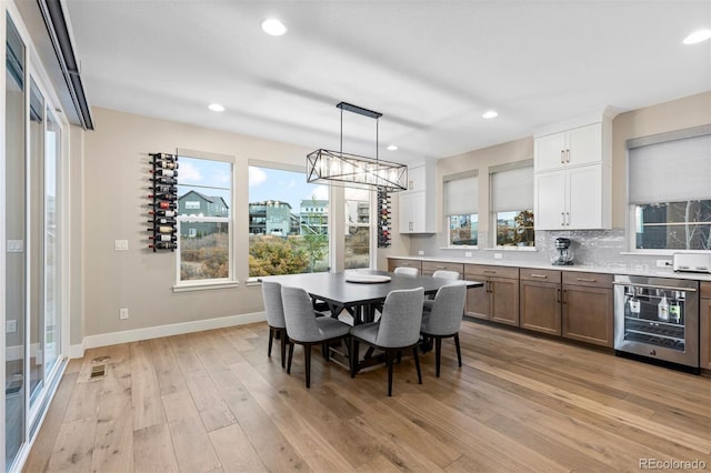 dining room with beverage cooler and light hardwood / wood-style floors