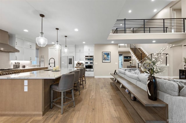 kitchen with white cabinets, pendant lighting, a large island with sink, and light stone countertops