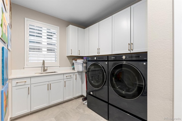 clothes washing area with cabinets, washing machine and clothes dryer, and sink