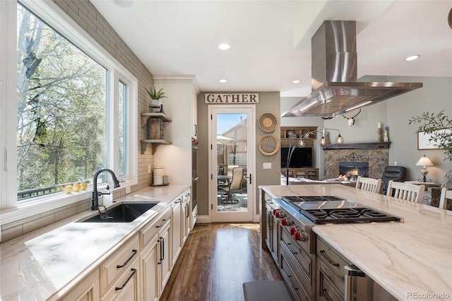 3002 S Oak Way, Lakewood, CO 80227 - kitchen with island exhaust hood, a sink, stainless steel gas stovetop, open floor plan, and light stone counters