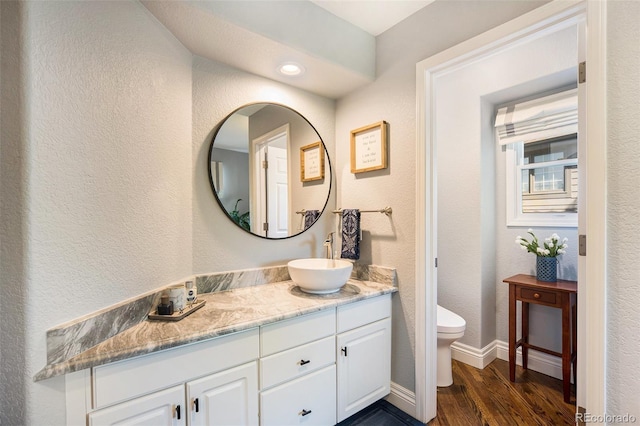 3002 S Oak Way, Lakewood, CO 80227 - bathroom featuring wood finished floors, toilet, vanity, baseboards, and a textured wall
