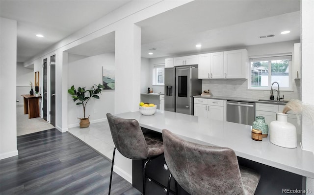 kitchen with dark wood-type flooring, sink, appliances with stainless steel finishes, and white cabinets