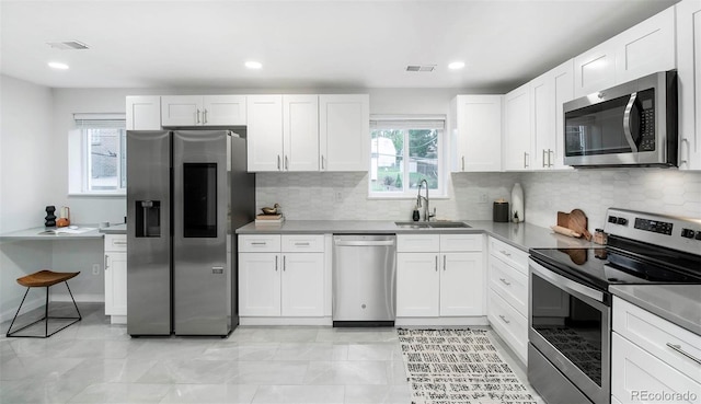 kitchen featuring appliances with stainless steel finishes, sink, white cabinets, and decorative backsplash