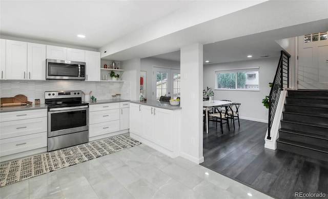 kitchen with light hardwood / wood-style flooring, stainless steel appliances, white cabinetry, and tasteful backsplash