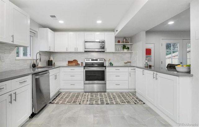 kitchen featuring appliances with stainless steel finishes, white cabinetry, sink, and decorative backsplash