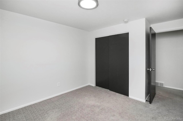 unfurnished bedroom featuring light carpet and a closet