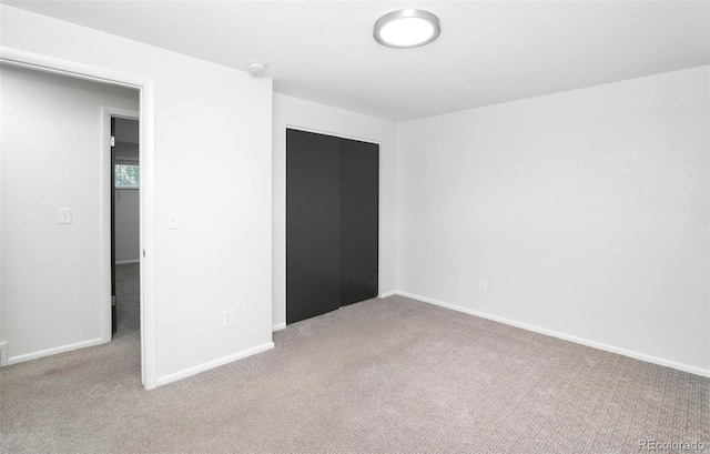 unfurnished bedroom with light carpet and a closet