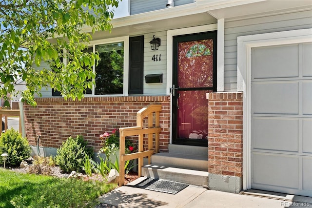 411 S Cody Ct, Lakewood, CO 80226 - view of exterior entry featuring brick siding, covered porch, and a garage