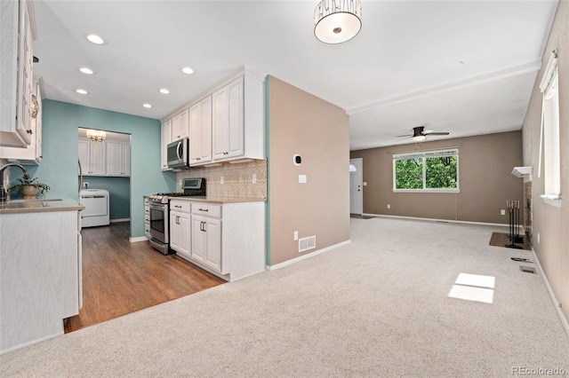 411 S Cody Ct, Lakewood, CO 80226 - kitchen featuring appliances with stainless steel finishes, washer / clothes dryer, white cabinetry, a sink, and decorative backsplash