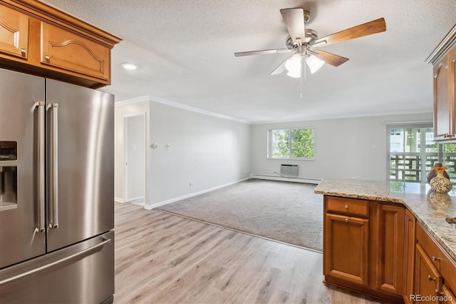 kitchen featuring baseboard heating, high quality fridge, light carpet, light stone counters, and crown molding