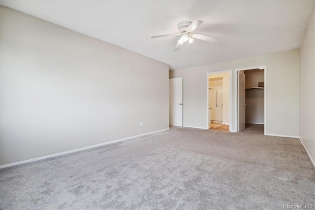 unfurnished bedroom featuring ceiling fan, light colored carpet, a closet, and a walk in closet