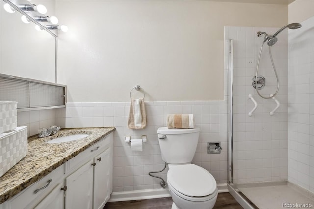 bathroom featuring tile walls, toilet, vanity, and tiled shower