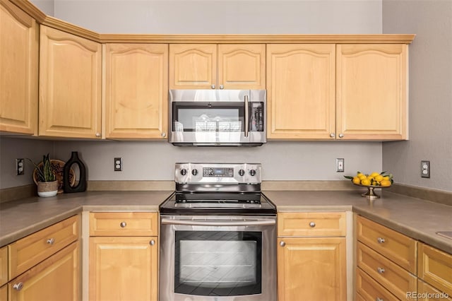 kitchen with light brown cabinetry, appliances with stainless steel finishes, and dark countertops