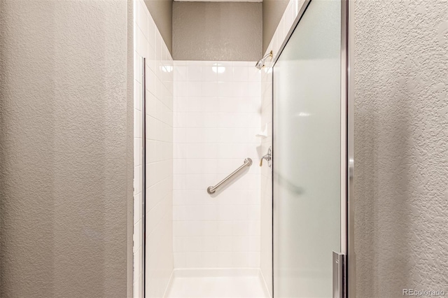 full bathroom with a textured wall and a shower stall